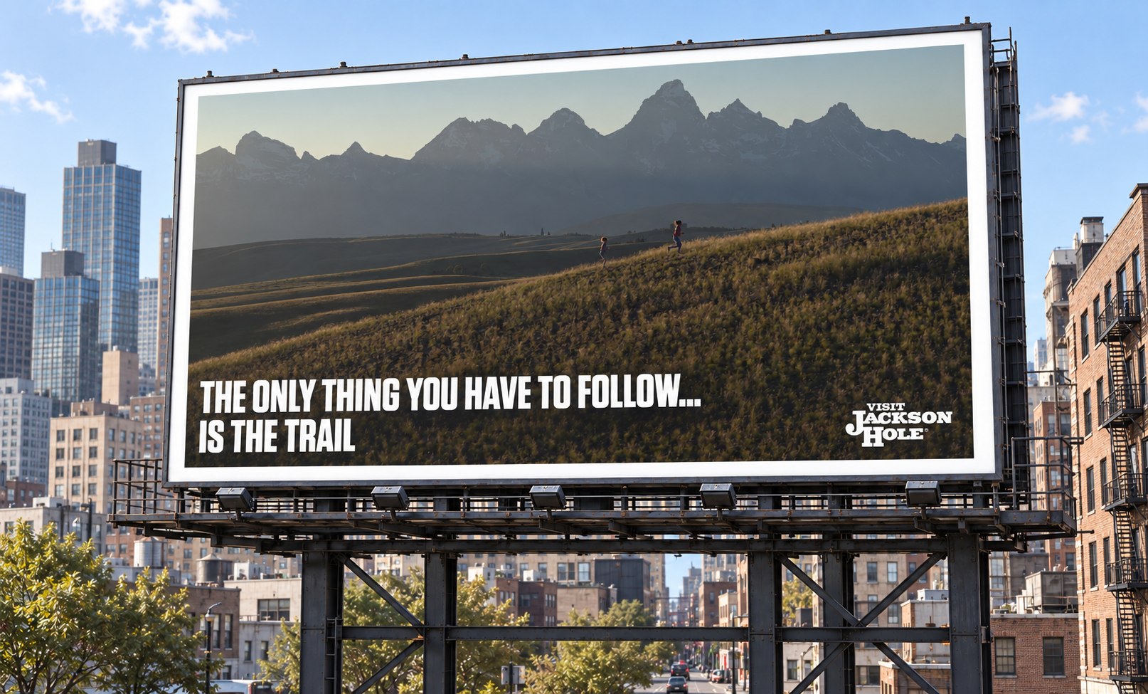 Billboard: 'The only thing you have to follow... is the trail,' over two kids running a trail toward the Tetons